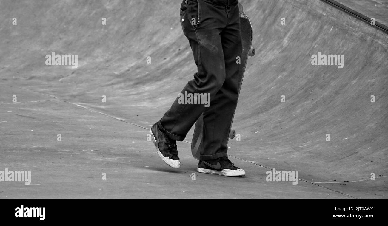 A grayscale shot of an unknown skater in a skatepark Stock Photo