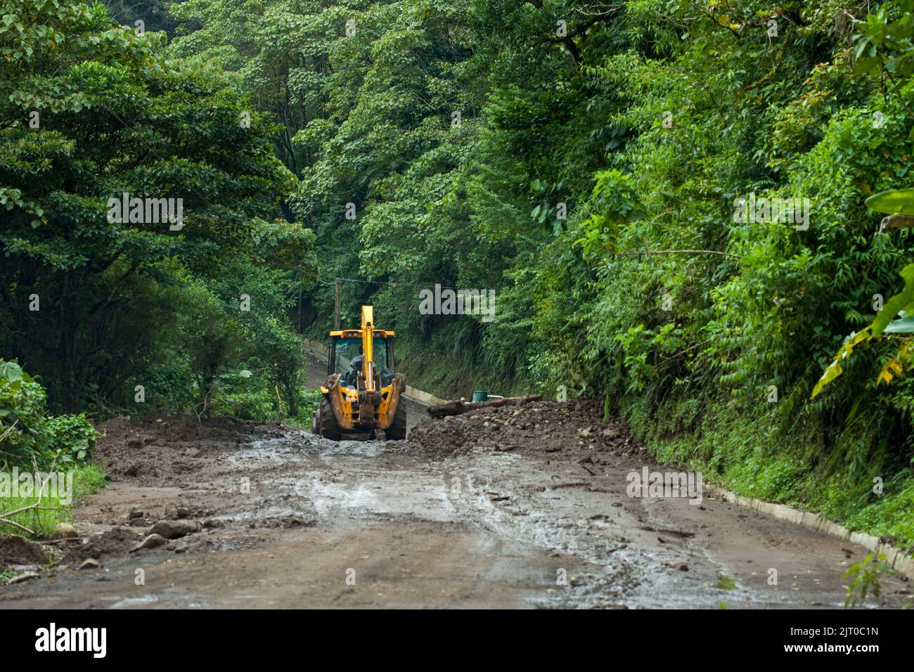 A backhoe clears the road of mud after a mudslide caused by heavy rain