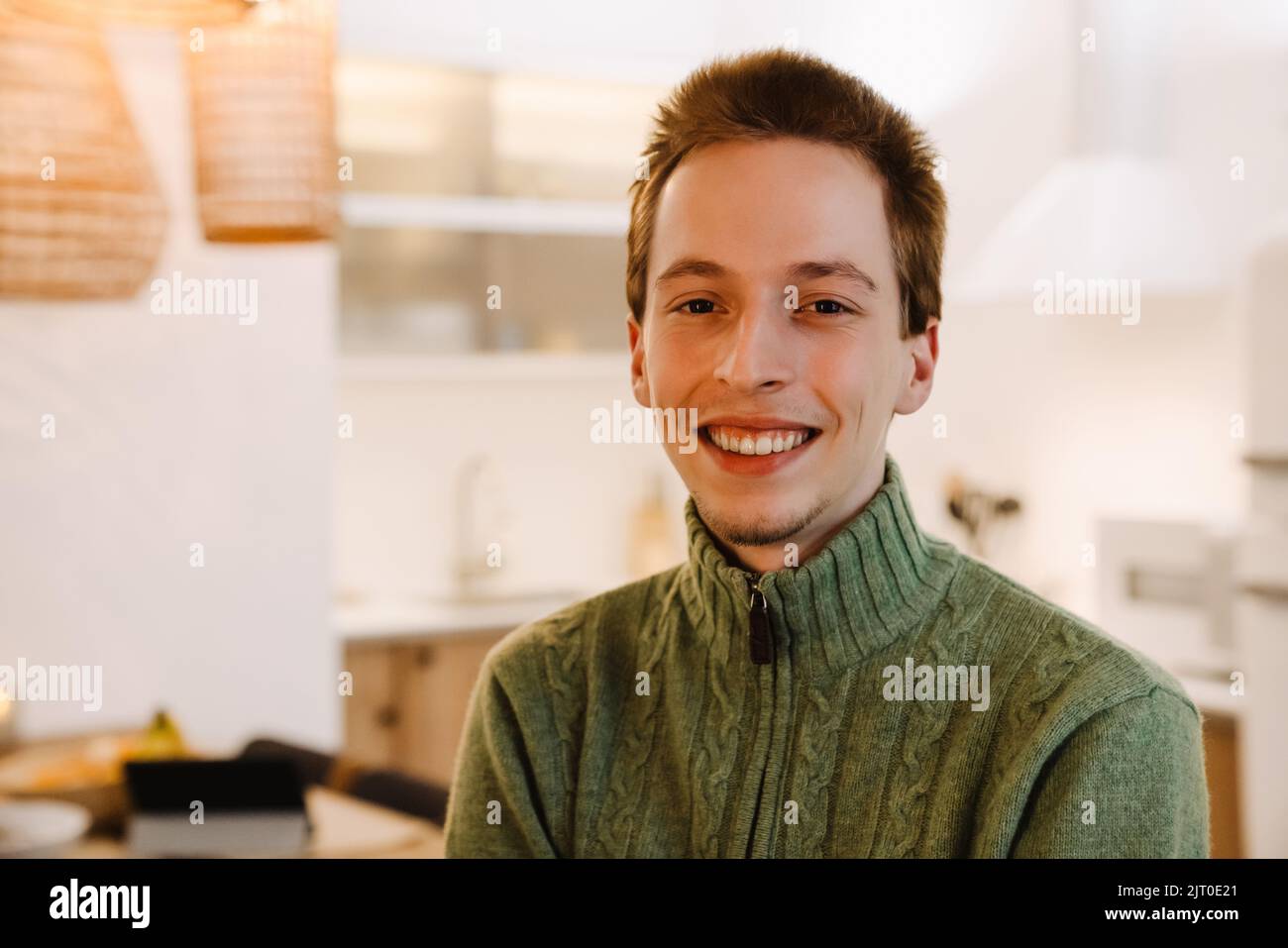 European ginger man smiling and looking at camera while posing in home ...
