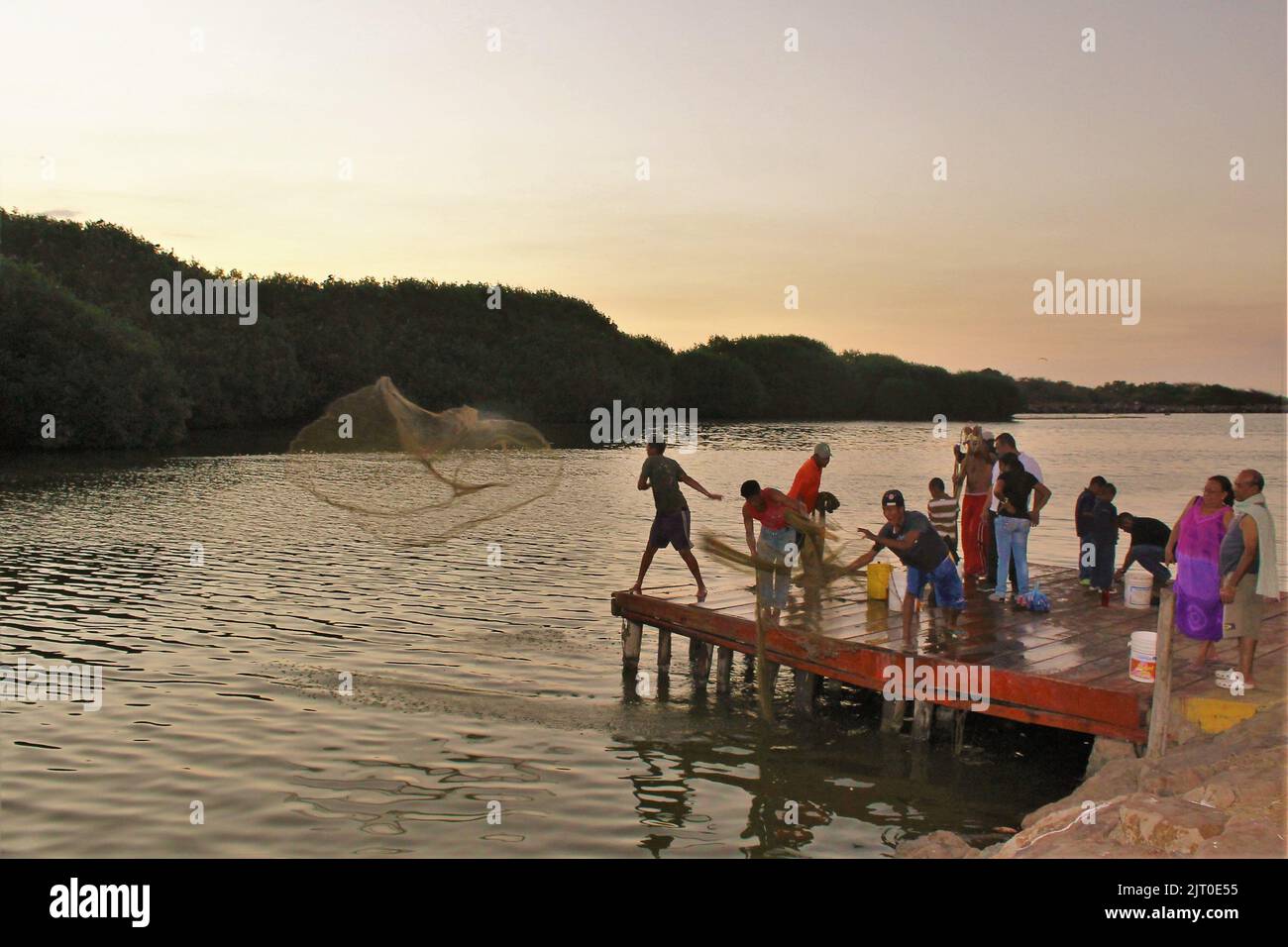 A group of shrimp fishermen on a dock throwing their nets into the water Stock Photo