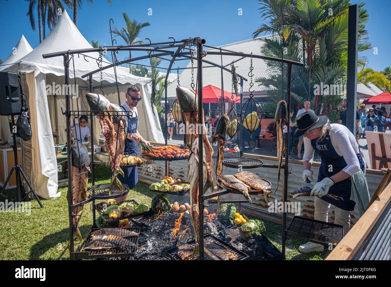 Two cooks roasting fish and varied vegetables over an open flame barbecue at Taste Port Douglas food & drink Festival in Australia. Stock Photo