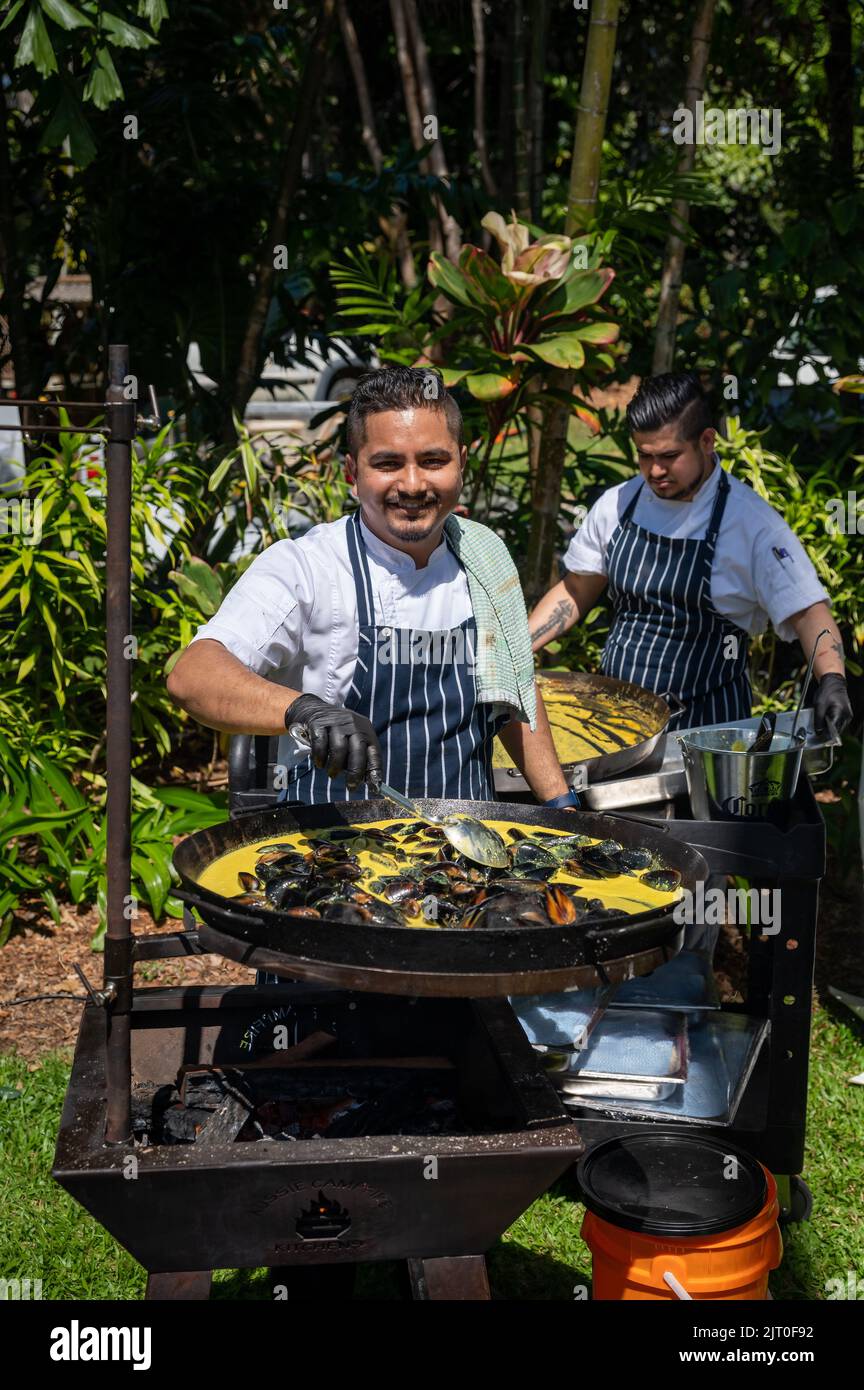 Chefs outside in front of a large woks proudly cooking curried mussels at the Sheraton Mirage Taste Port Douglas Food and Drink festival  Australia. Stock Photo