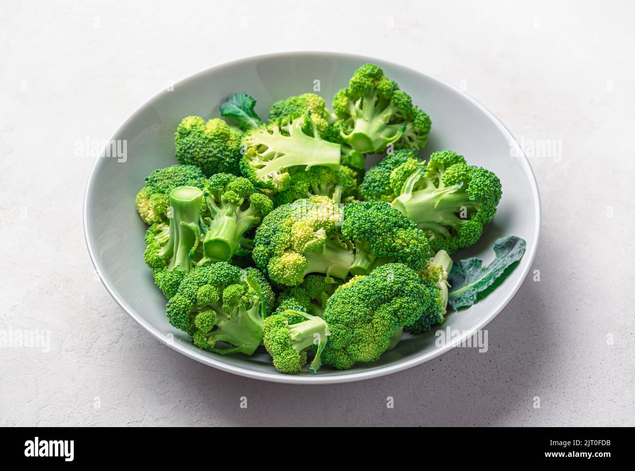 Broccoli in a plate on a gray wooden background. Cooking broccoli. Stock Photo