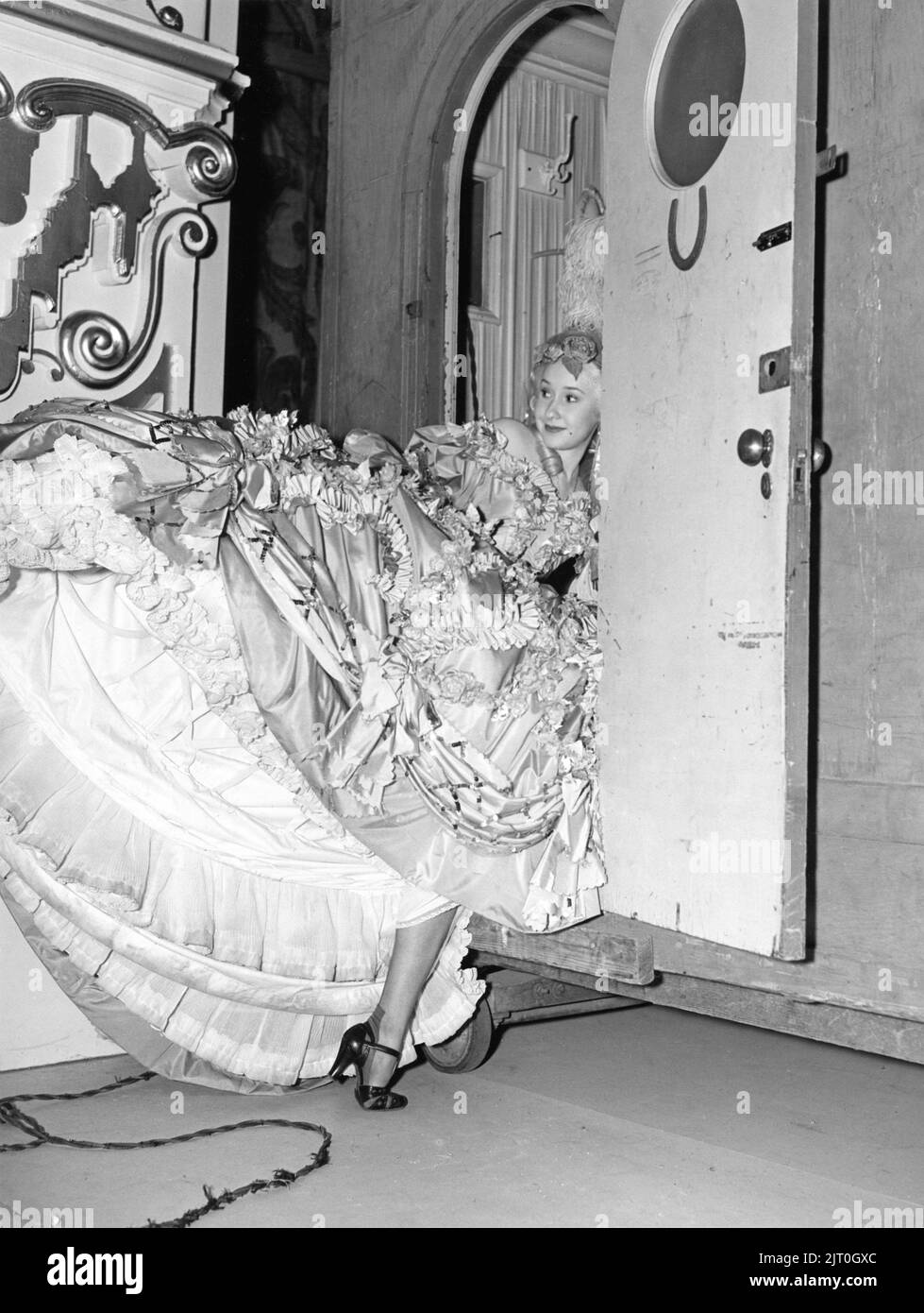 Female / Girl Extra has trouble with her Hoop Dress at Dressing Room door on set candid during filming of MARIE ANTOINETTE 1938 director W.S. VAN DYKE art direction Cedric Gibbons gowns by Gilbert Adrian producer Hunt Stromberg Metro Goldwyn Mayer Stock Photo