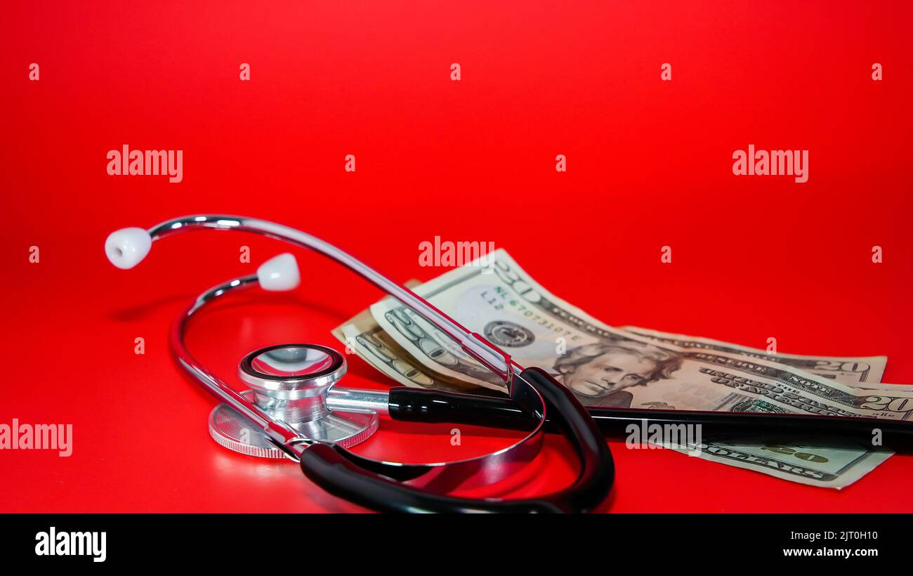 Stethoscope and money on red background with copy space above Stock Photo