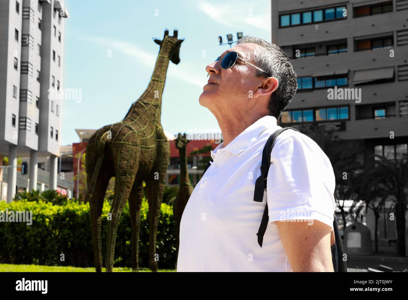 Old man in a white polo and a backpack looking the attractions in ...