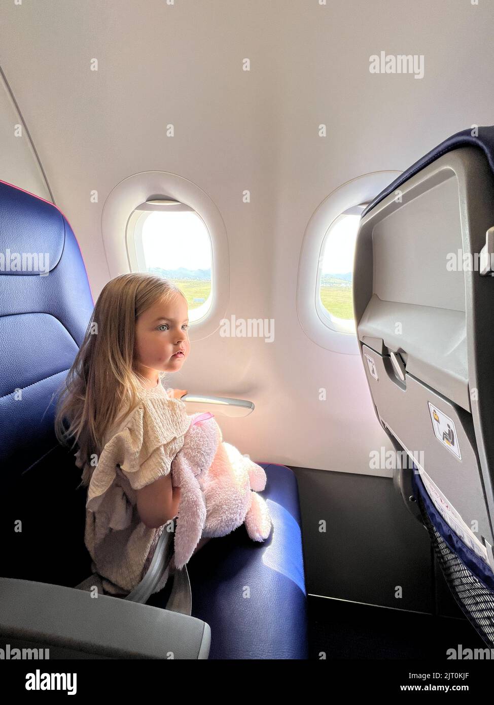 Little girl sits in an airplane seat near the porthole Stock Photo - Alamy