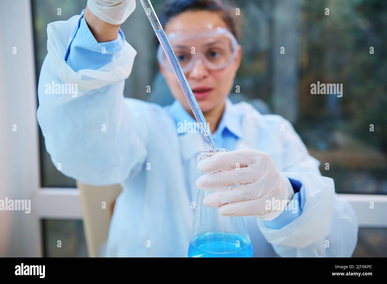 Focus on laboratory pipette in the hands of blurred scientist