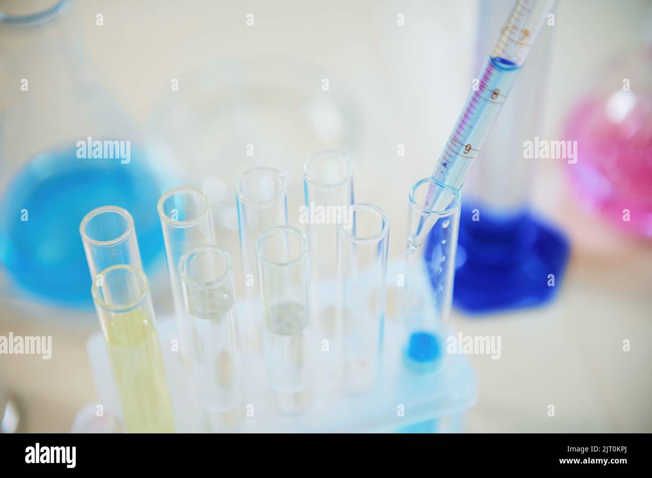 Focus on dripping reagent from a glass laboratory pipette into a test tube with blue chemical
