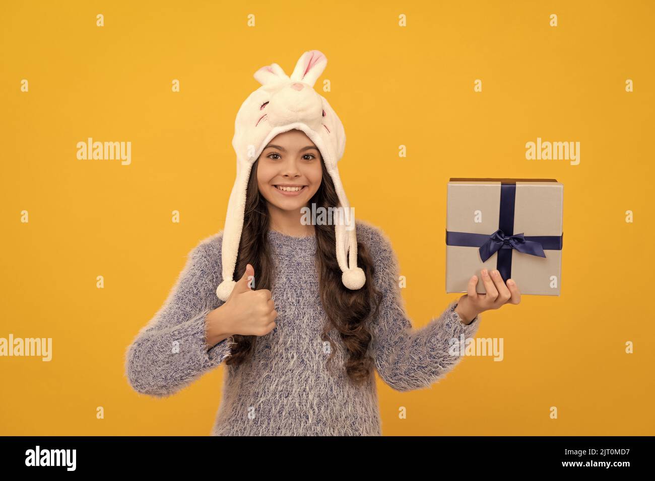 happy child in sweater and hat hold present box on yellow background, shopping Stock Photo