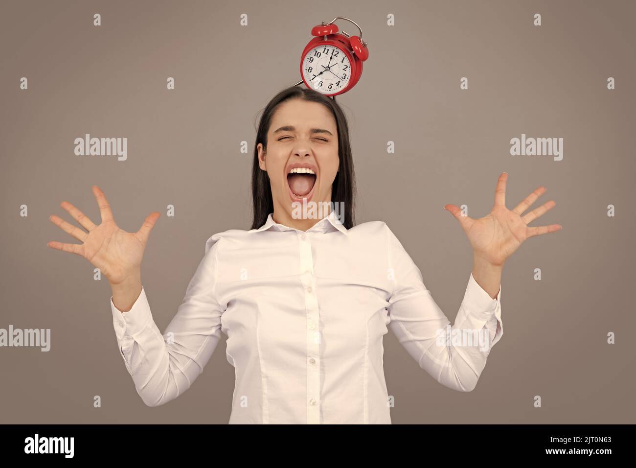Funny girl hold alarm clock isolated on gray background. Stock Photo