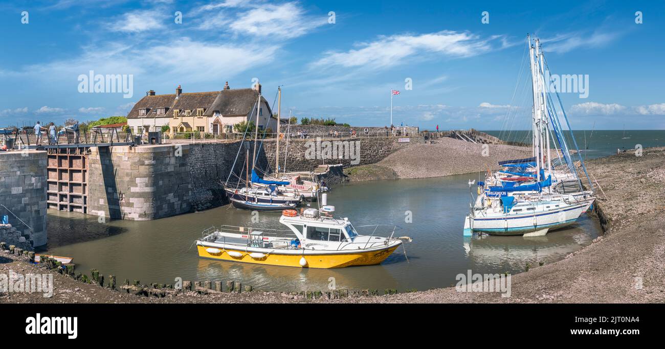 On a beautiful day in August, people enjoy the sunshine at Porlock Weir as the incoming tide starts to flood into the small harbour. Stock Photo
