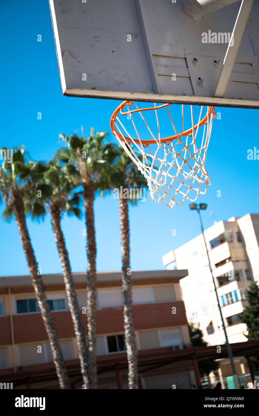 A vertical closeup of a basketball hoop with the sky and trees in the background Stock Photo Alamy