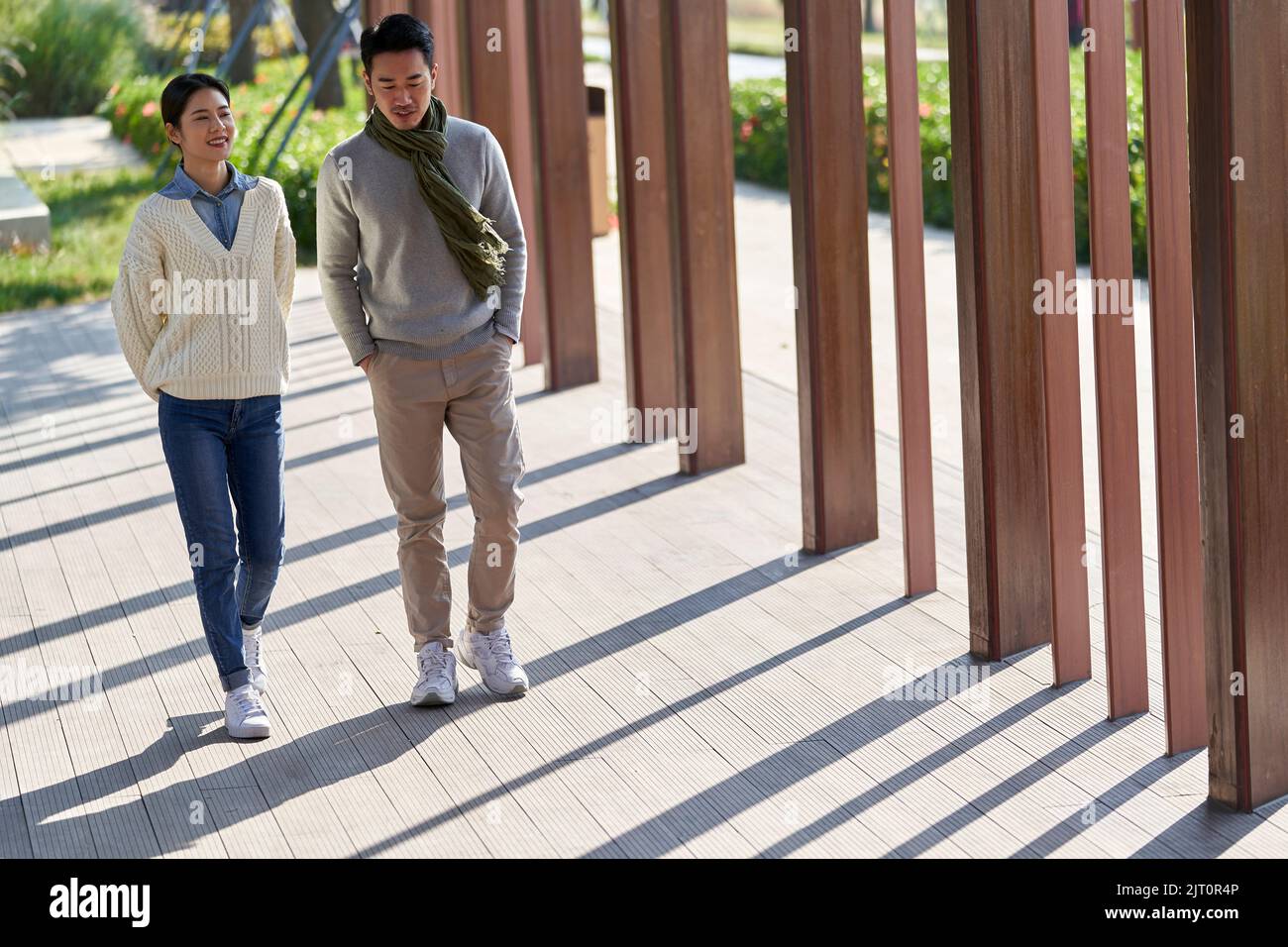 young asian dating couple walking and chatting outdoors in park happy and smiling Stock Photo