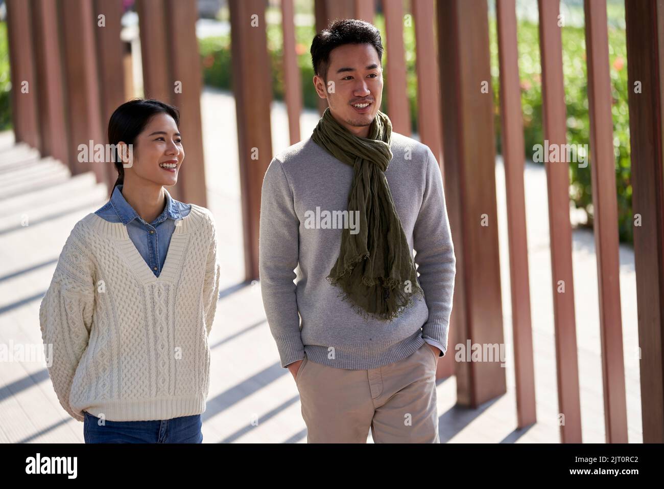 young asian dating couple walking and chatting outdoors in park happy and smiling Stock Photo