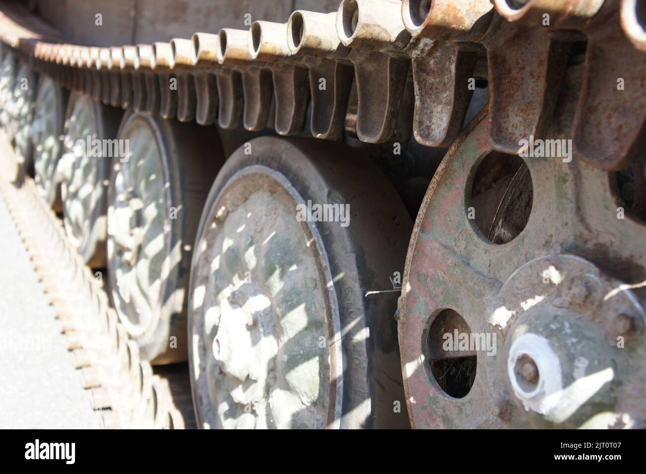 Tank track. View of the front part of the green caterpillar of the tank standing on the ground with the wheels close-up Stock Photo