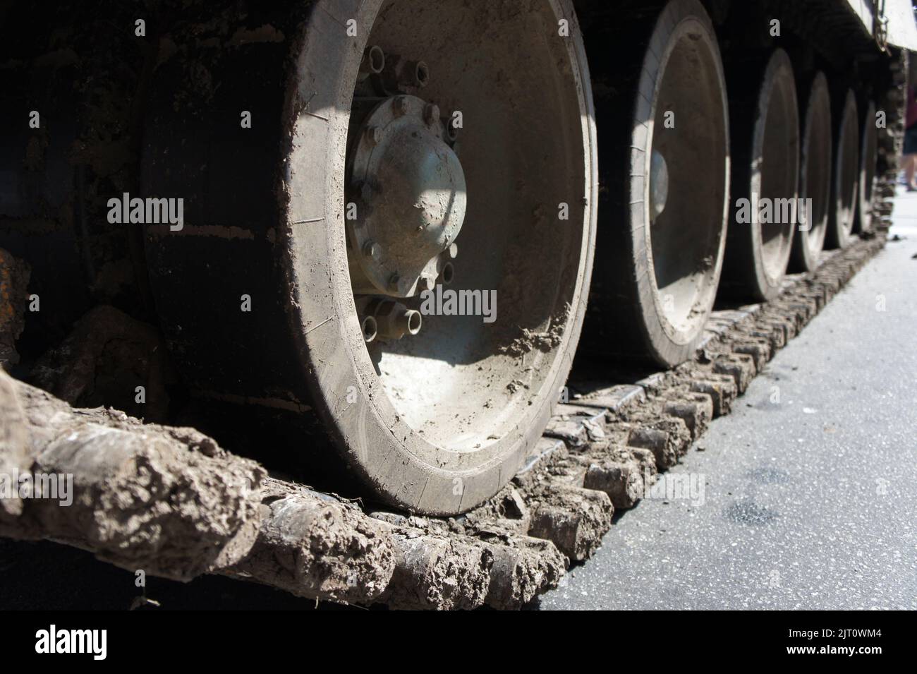 Tank track. View of the front part of the green caterpillar of the tank standing on the ground with the wheels close-up Stock Photo