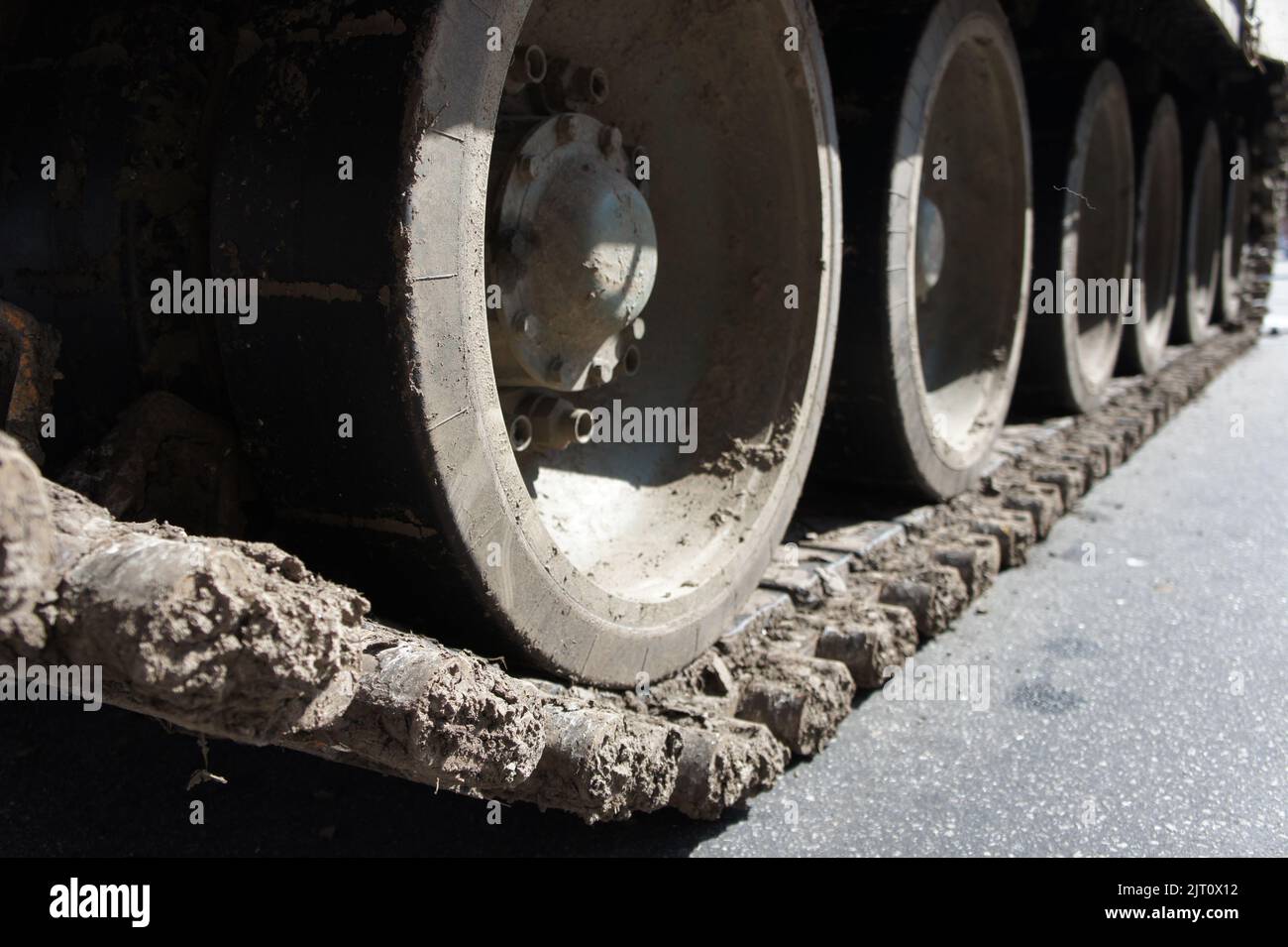 Tank track. View of the front part of the green caterpillar of the tank standing on the ground with the wheels close-up Stock Photo