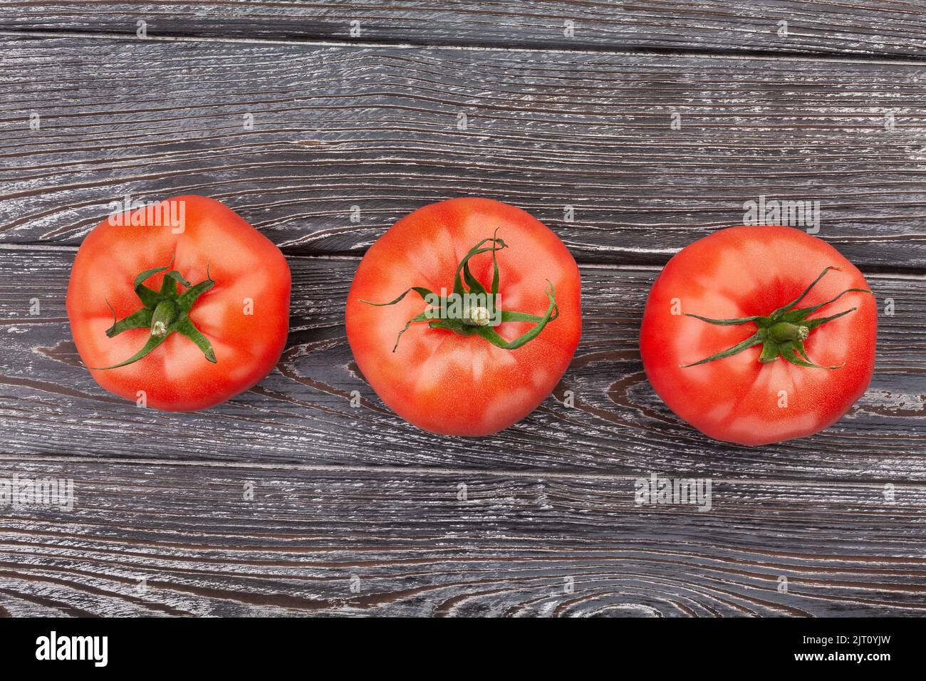 three tomatoes on wood background Stock Photo