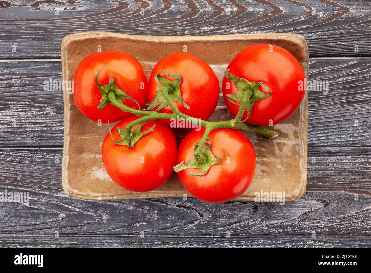 tomato on a plate on wood background Stock Photo