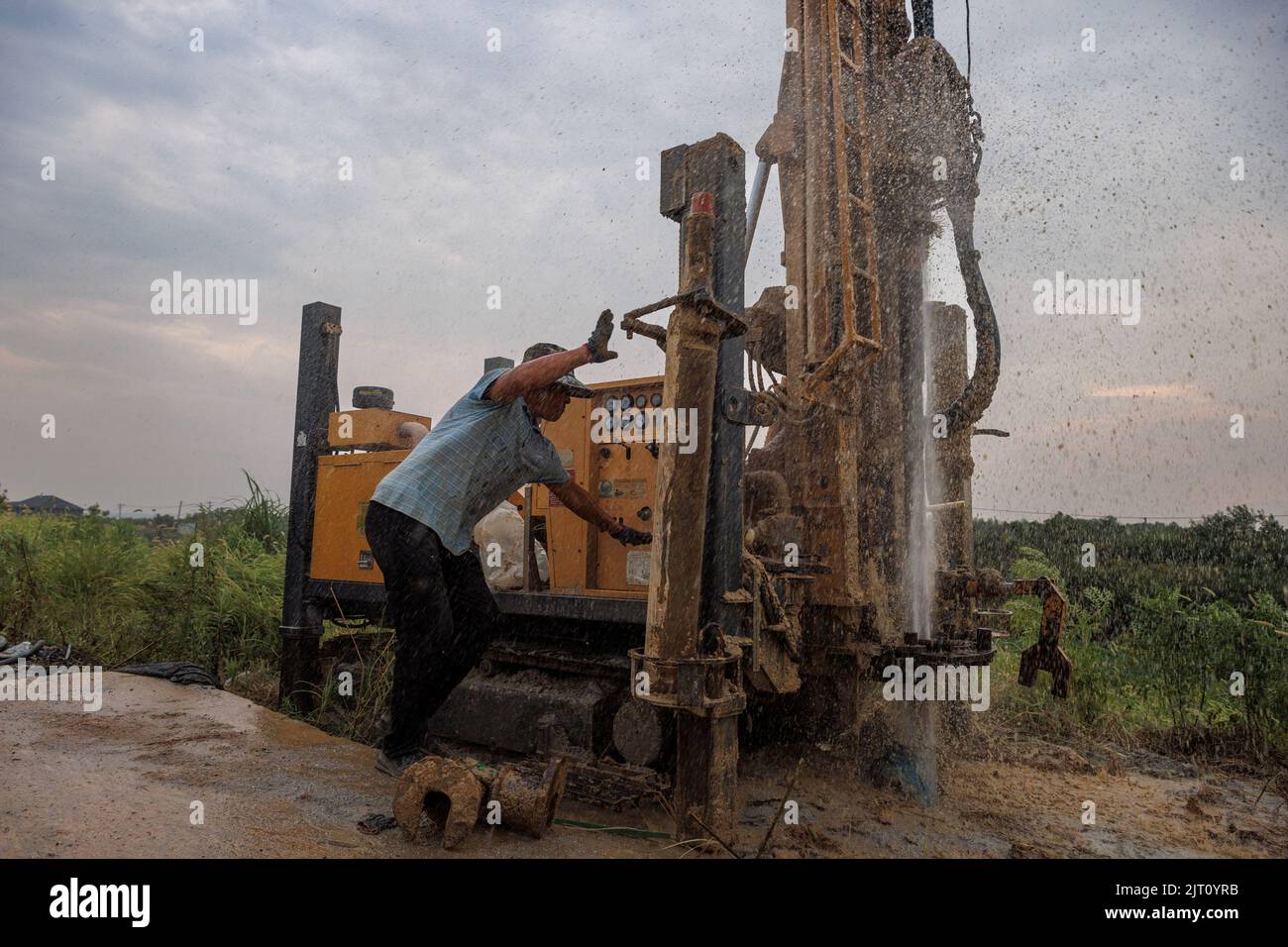 Head of a drilling crew Gao Pucha operates a machine as his drill hits water as the region experiences a drought outside Jiujiang city, Jiangxi province, China, August 27, 2022.  REUTERS/Thomas Peter Stock Photo