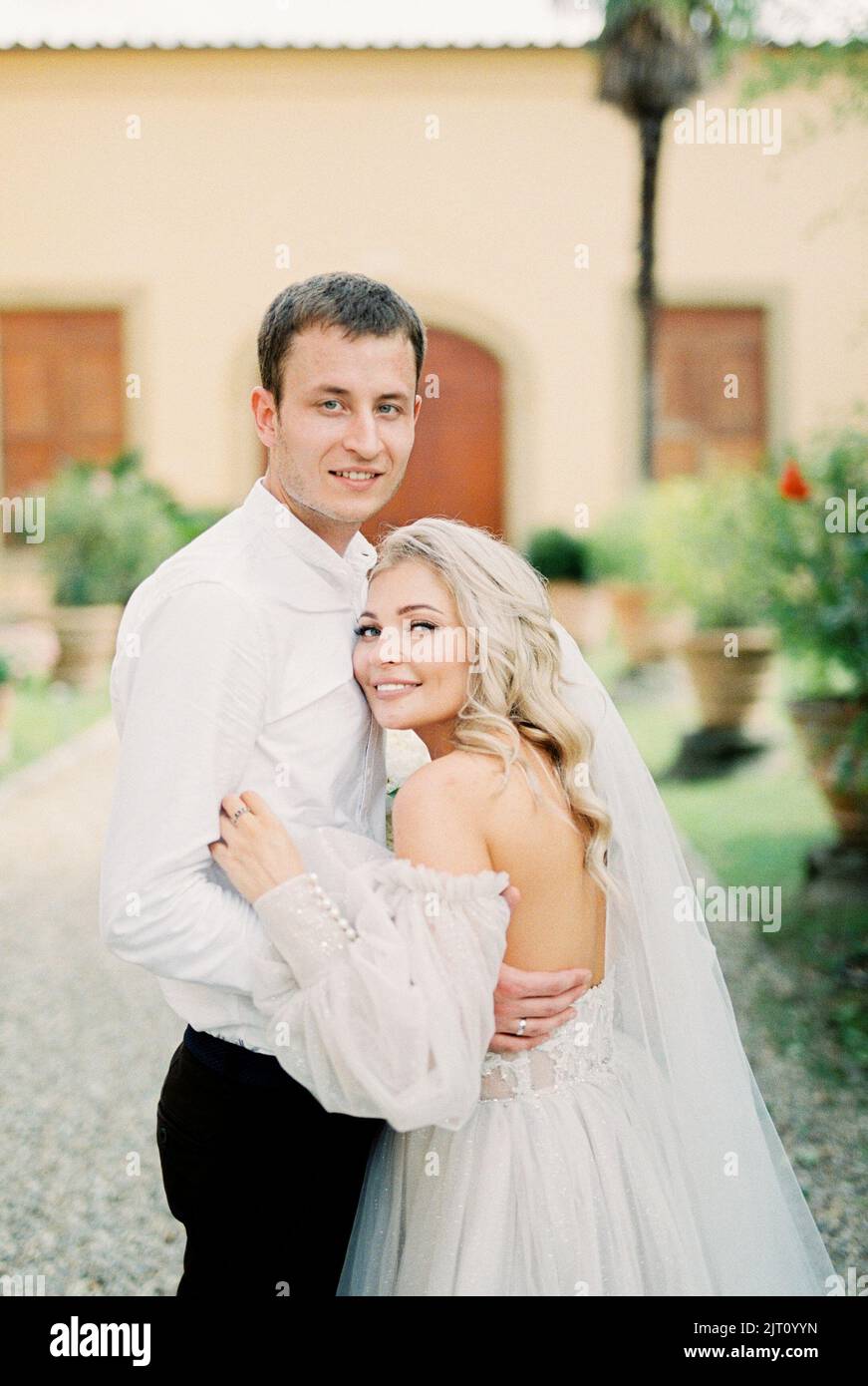Bride and groom stand hugging in the garden near the villa Stock Photo ...