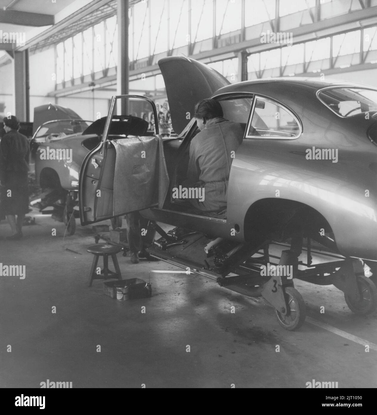Porsche history. A rare view of the Porsche car factory in Stuttgart Germany in the 1950s. In the factory building Porsche cars is seen in different stages of production on a assembly line where workers are installing and putting the Porsche cars together. 1951. Stock Photo