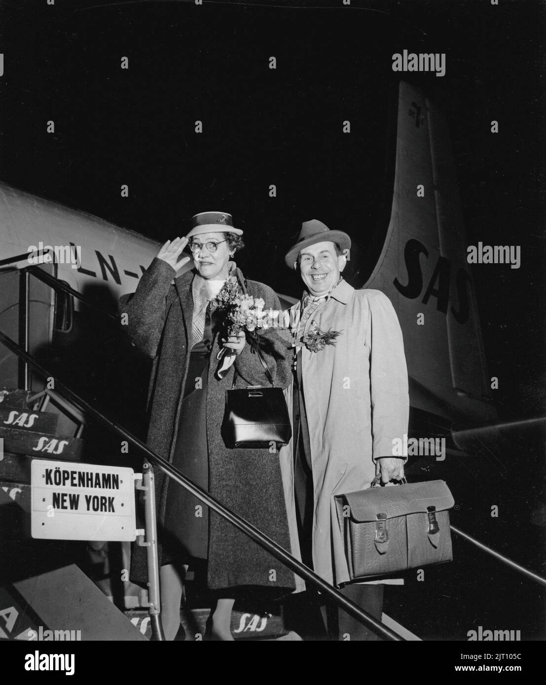 1950s vacation. A couple standing on the stairs before boarding the airplane, waving goodbye, looking happy. On route to New York via Copenhagen. Sweden 1957 Stock Photo