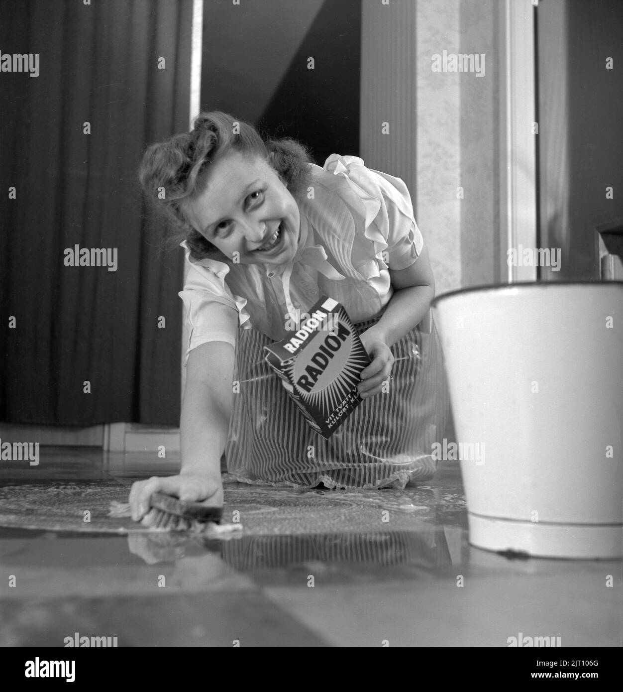 Cleaning the floor back then. A young woman is lying on the floor and is scrubbing to get the floor clean. Sweden 1952 Conard ref 2220 Stock Photo