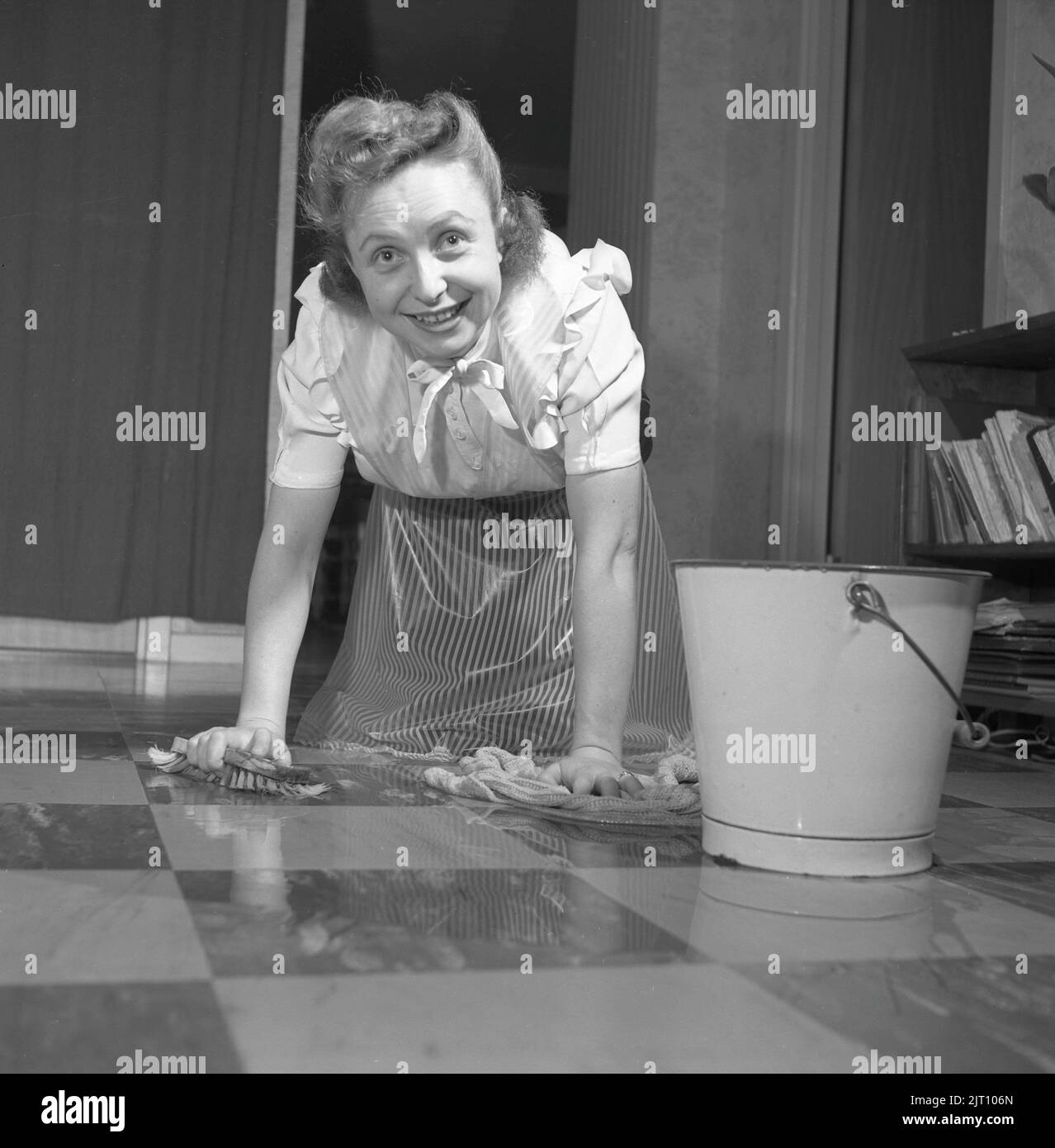 Cleaning the floor back then. A young woman is lying on the floor and is scrubbing to get the floor clean. Sweden 1952 Conard ref 2220 Stock Photo