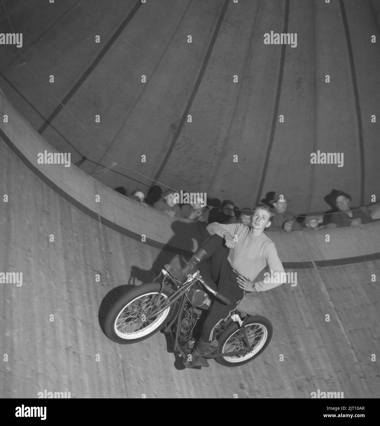 Motorcyclist in the 1940s. A A young man on his motorcycle during a show in The wall of death (sometimes known as The wall of death, motordrome, silodrome. Wall of death is a wooden planked barrel shaped arena where spectators watch from the top as motorcycles or other motorised vehicles ride around it at high speed,often performing other stunts. Sweden 1947 Conard ref 1103 Stock Photo