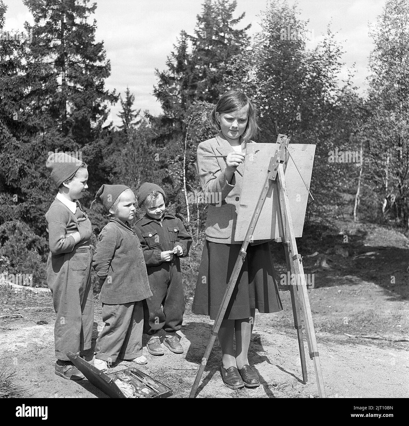 Young artist. A teenage girl paints something that fascinates the three