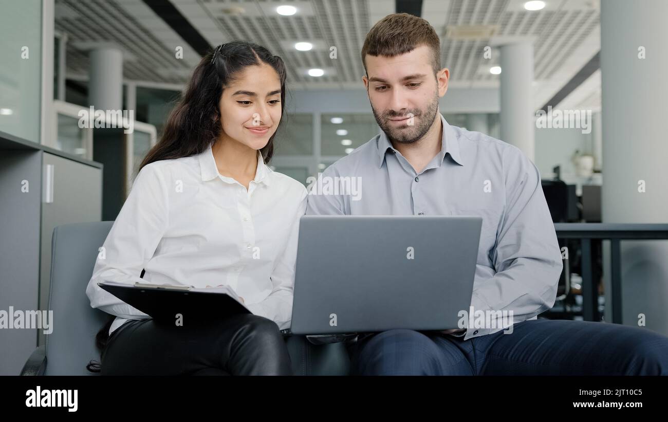 Young man and woman office workers creative team colleagues discussing online project develop strategy using laptop exchange ideas talks in workplace Stock Photo