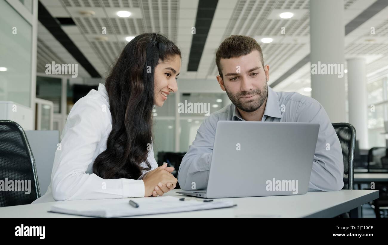 Young recruit woman presenting project on laptop to mentor professional female manager training new male worker explains online services to client on Stock Photo