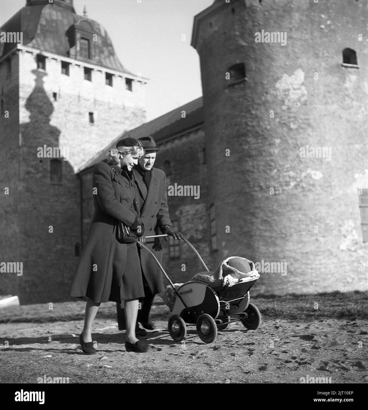 Parents in the 1940s. A proud mother and father are walking with their child in the baby carriage. The baby carriage has a typical 1940s design with a wooden body painted in black and white. Kalmar Sweden 1945 Kristoffersson ref R110-4 Stock Photo