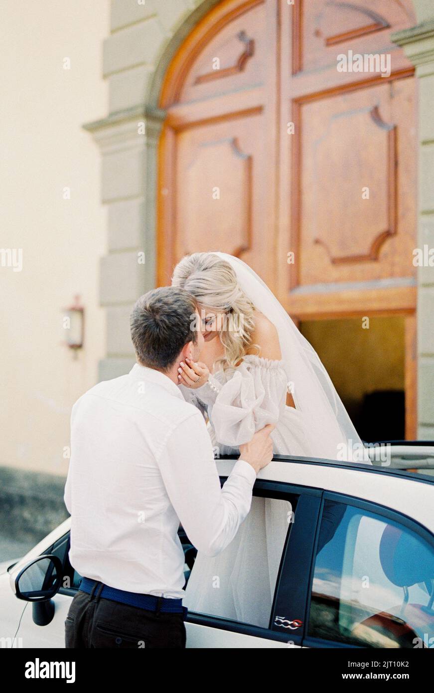 Groom kisses bride standing in the sunroof of the car Stock Photo - Alamy