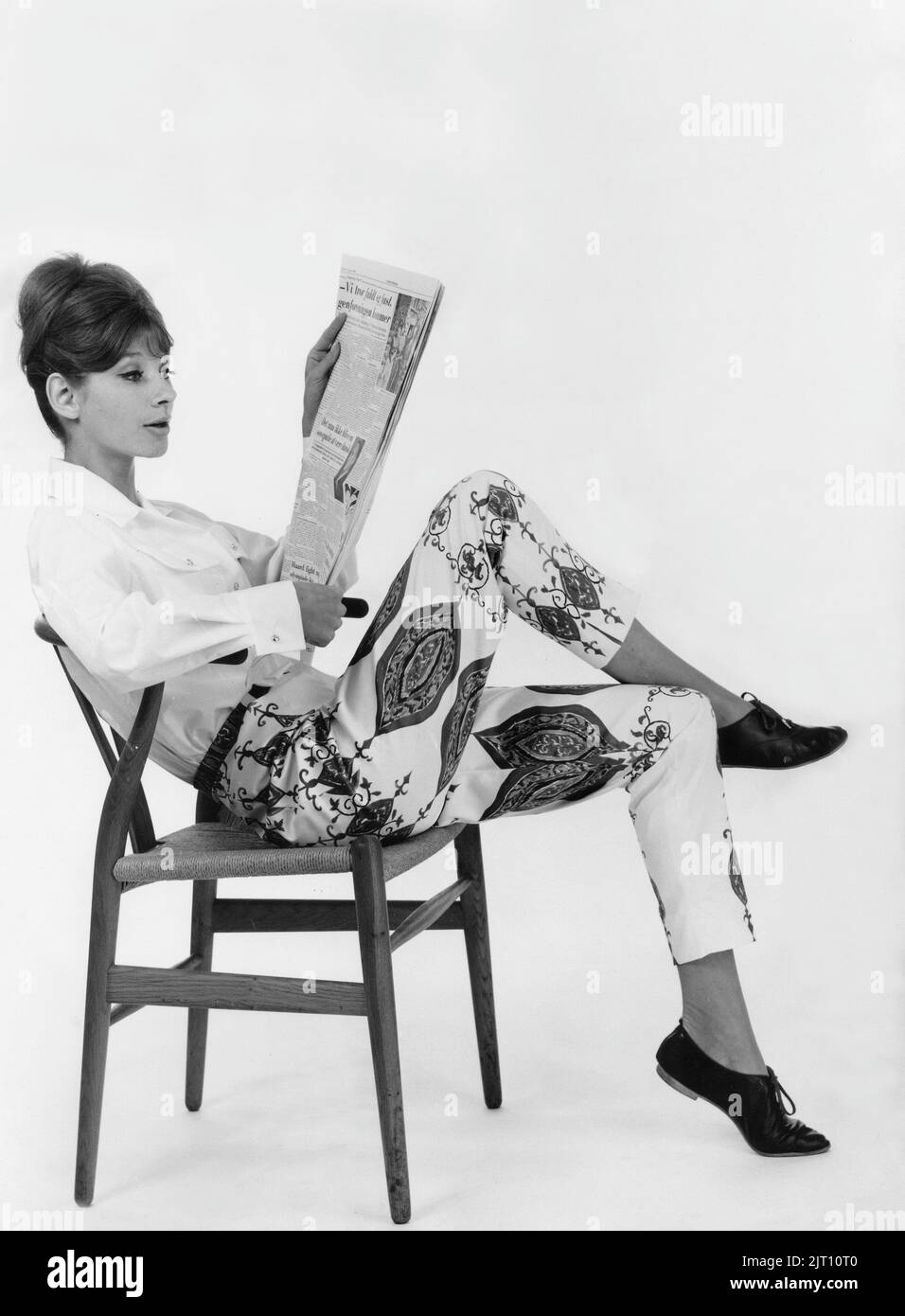 Woman of the 1960s. She sits comfortably and read from the daily paper. Sweden 1960 Stock Photo