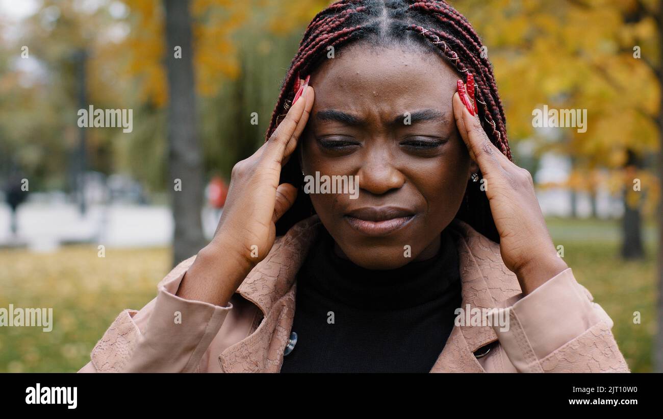 Close-up unhealthy frustrated woman holding head suffering from headache feels burning pain squeezing pressure suffers from chronic migraine unhappy Stock Photo