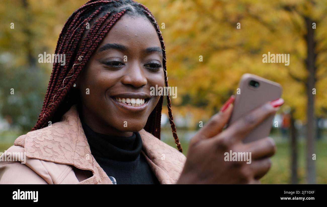 Close-up young happy woman standing in autumn park communicates video chat on smartphone friendly online conversation joyful smiling girl talking with Stock Photo