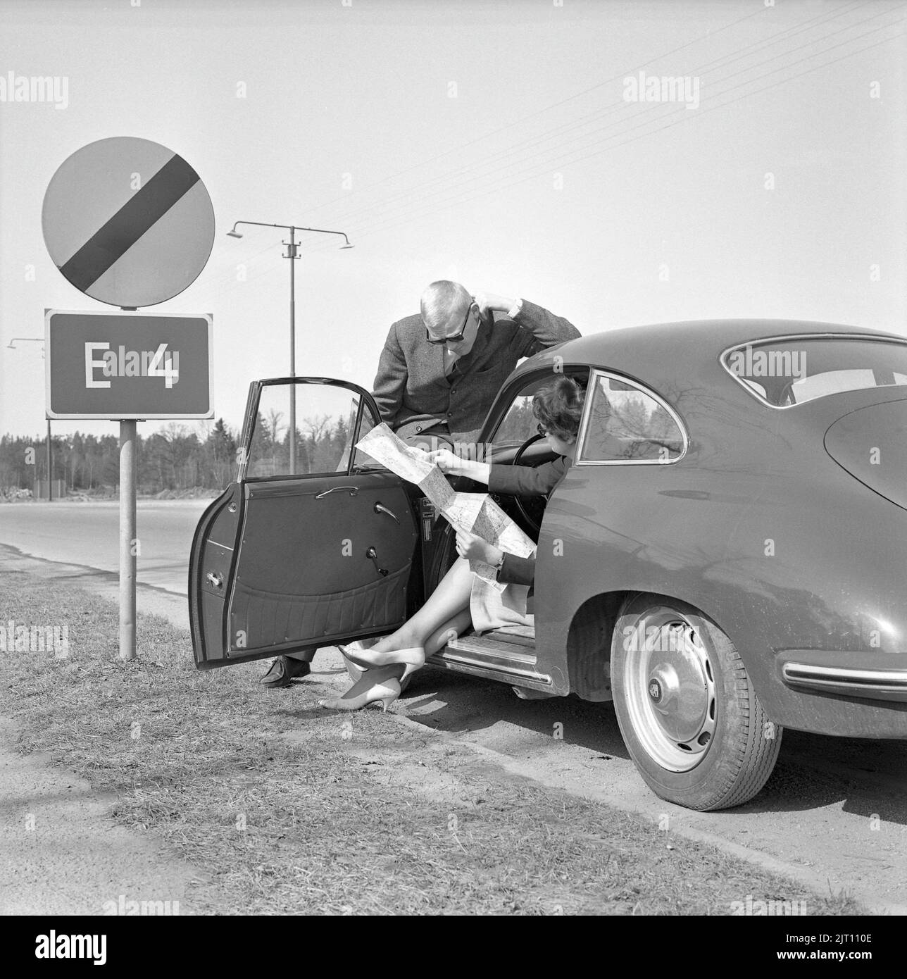 Couple in the 1960s. A young couple in their Porsche sports car has stopped along the road to study the map where to go. Sweden 1962 Stock Photo