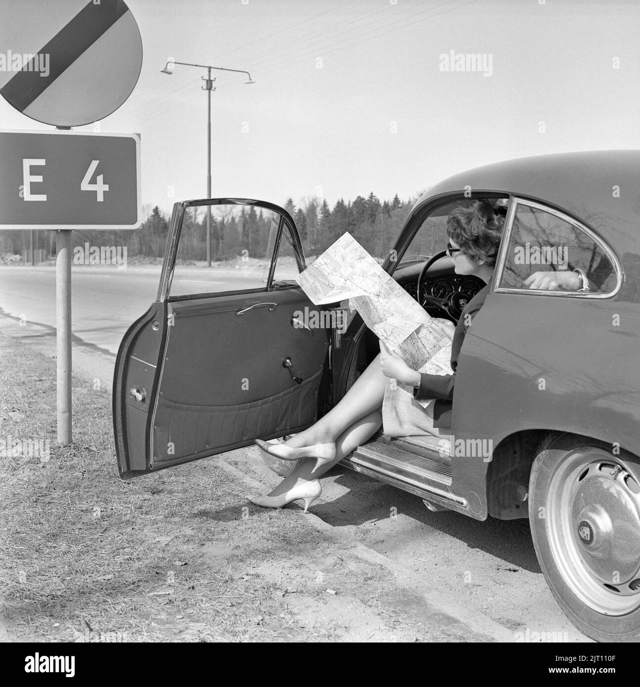 Couple in the 1960s. A young couple in their Porsche sports car has stopped along the road to study the map where to go. Sweden 1962 Stock Photo