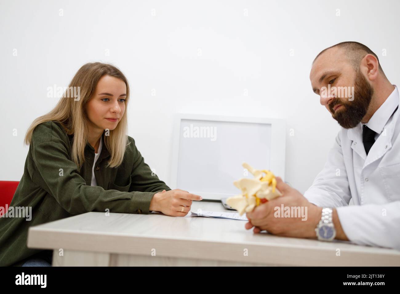Male surgeon shows intervertebral hernia on lumbar disc model to female