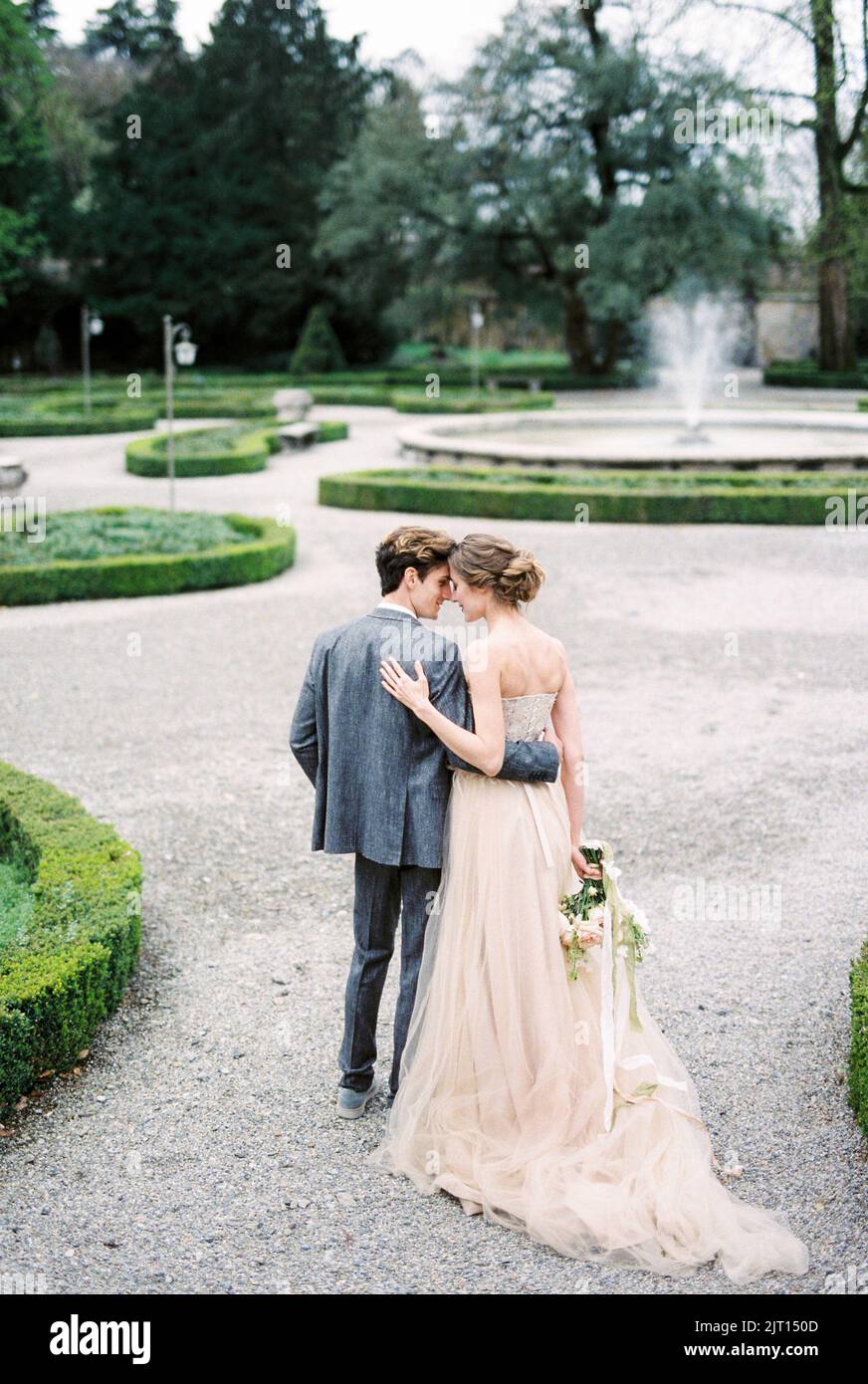 Bride and groom stand embracing in the park. Back view Stock Photo - Alamy