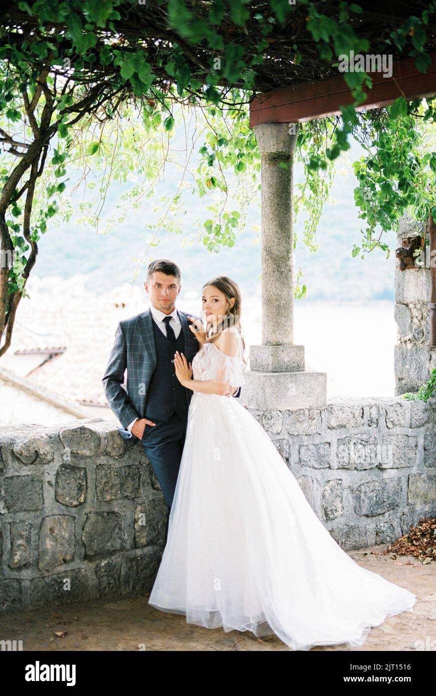 Bride and groom stand in a stone gazebo covered with ivy Stock Photo ...