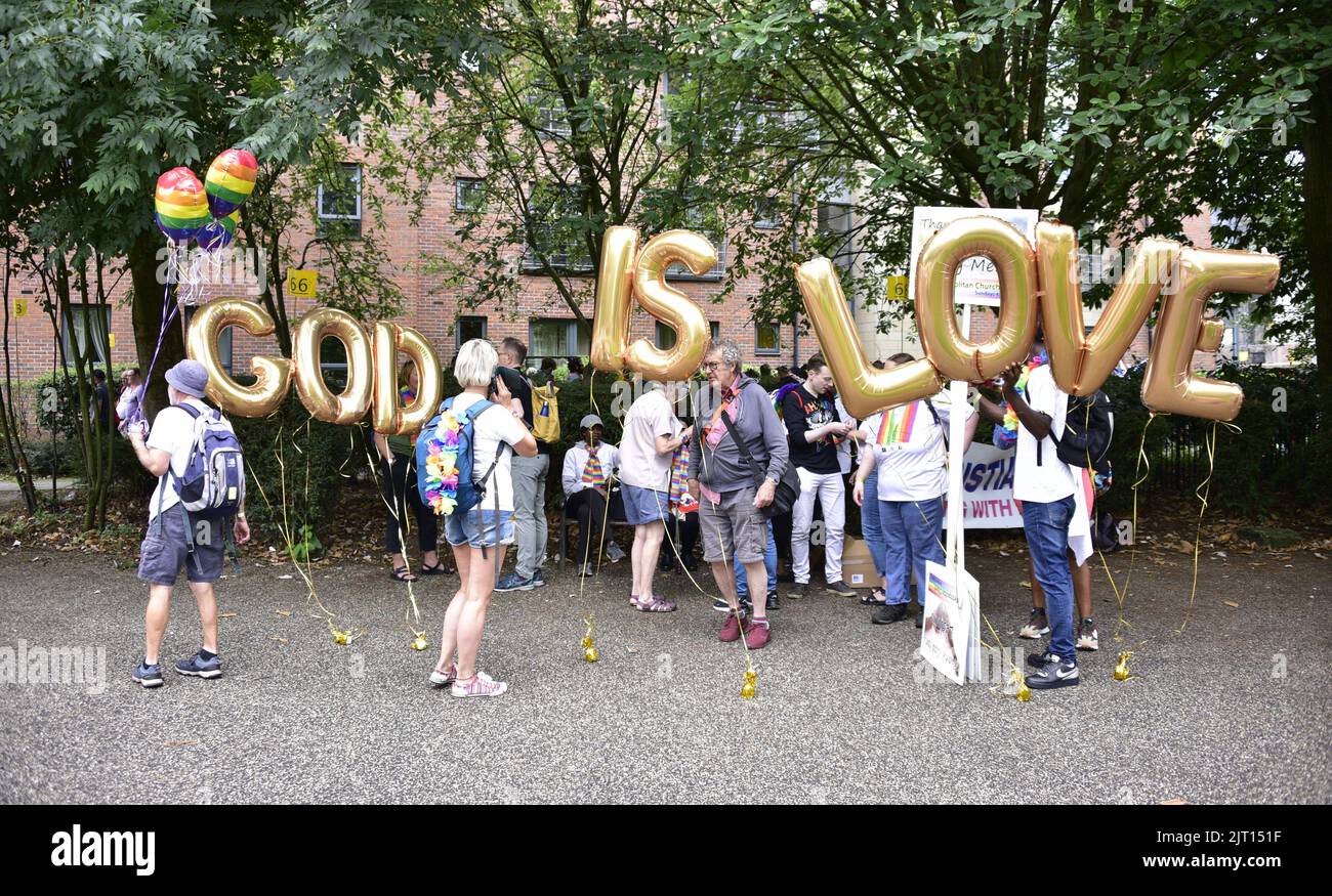 Manchester, UK. 27th August, 2022. A Christian group with 'God is Love' sign. Participants get ready to take part in the LGBTQ+ Pride parade, central Manchester, UK, as LGBTQ+ Pride continues over the Bank Holiday weekend 26th to 29th August. Organisers say: 'Manchester Pride is one of the UK's leading LGBTQ+ charities. Our vision is a world where LGBTQ+ people are free to live and love without prejudice. We’re part of a global Pride movement celebrating LGBTQ+ equality and challenging discrimination.' Credit: Terry Waller/Alamy Live News Stock Photo