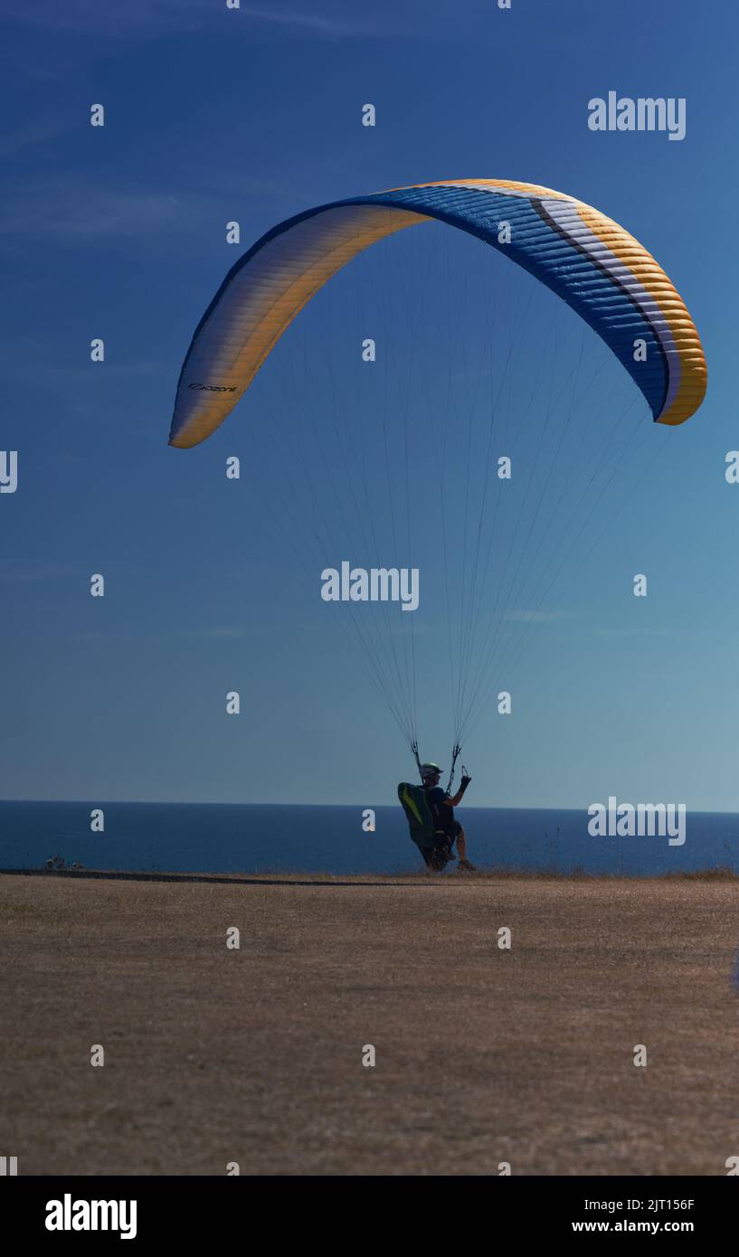 A paraglider landing on the beach in Hampshire, England against a clear