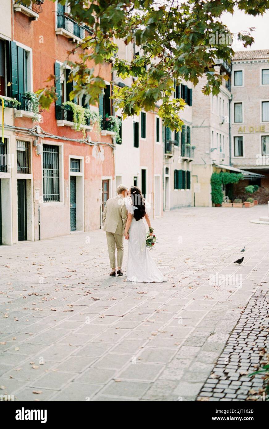 Groom hugs bride walking along the old street in Venice Stock Photo - Alamy
