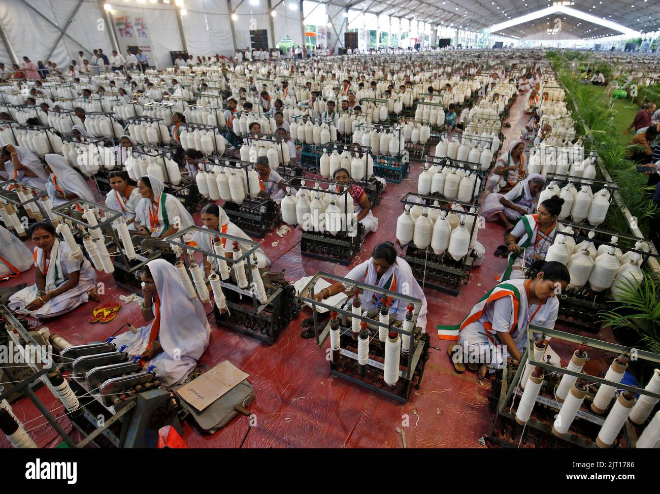 Artisans spin cotton on Amber Charkha, a cotton spinning wheel, during an event where 7500 artisans spin cotton live at same place to promote hand woven cotton cloth as part of the celebrations commemorating 75 years of India's Independence, in Ahmedabad, India, August 27, 2022. REUTERS/Amit Dave Stock Photo