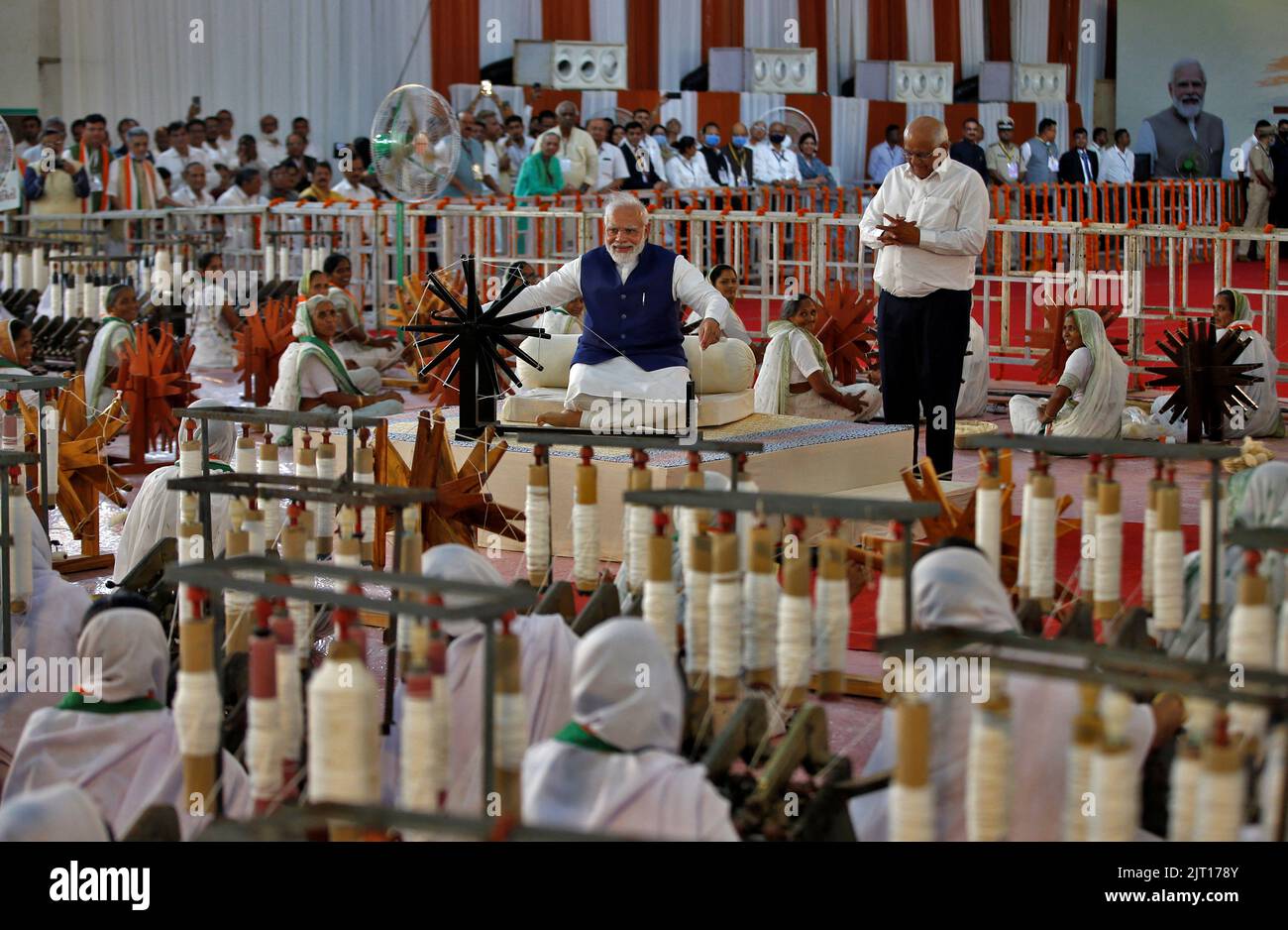India's Prime Minister Narendra Modi spins cotton on a wheel as Chief Minister of Gujarat Bhupendra Patel looks on during an event where 7500 artisans spin cotton live at same place to promote hand woven cotton cloth as part of the celebrations commemorating 75 years of India's Independence, in Ahmedabad, India, August 27, 2022. REUTERS/Amit Dave Stock Photo