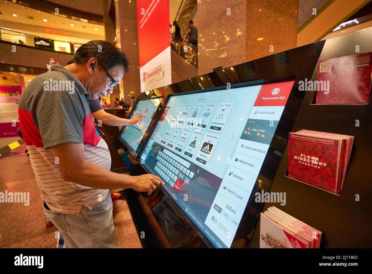 SINGAPORE - CIRCA JANUARY, 2020: man use interactive touch screen kiosk at Nge Ann City shopping center. Stock Photo
